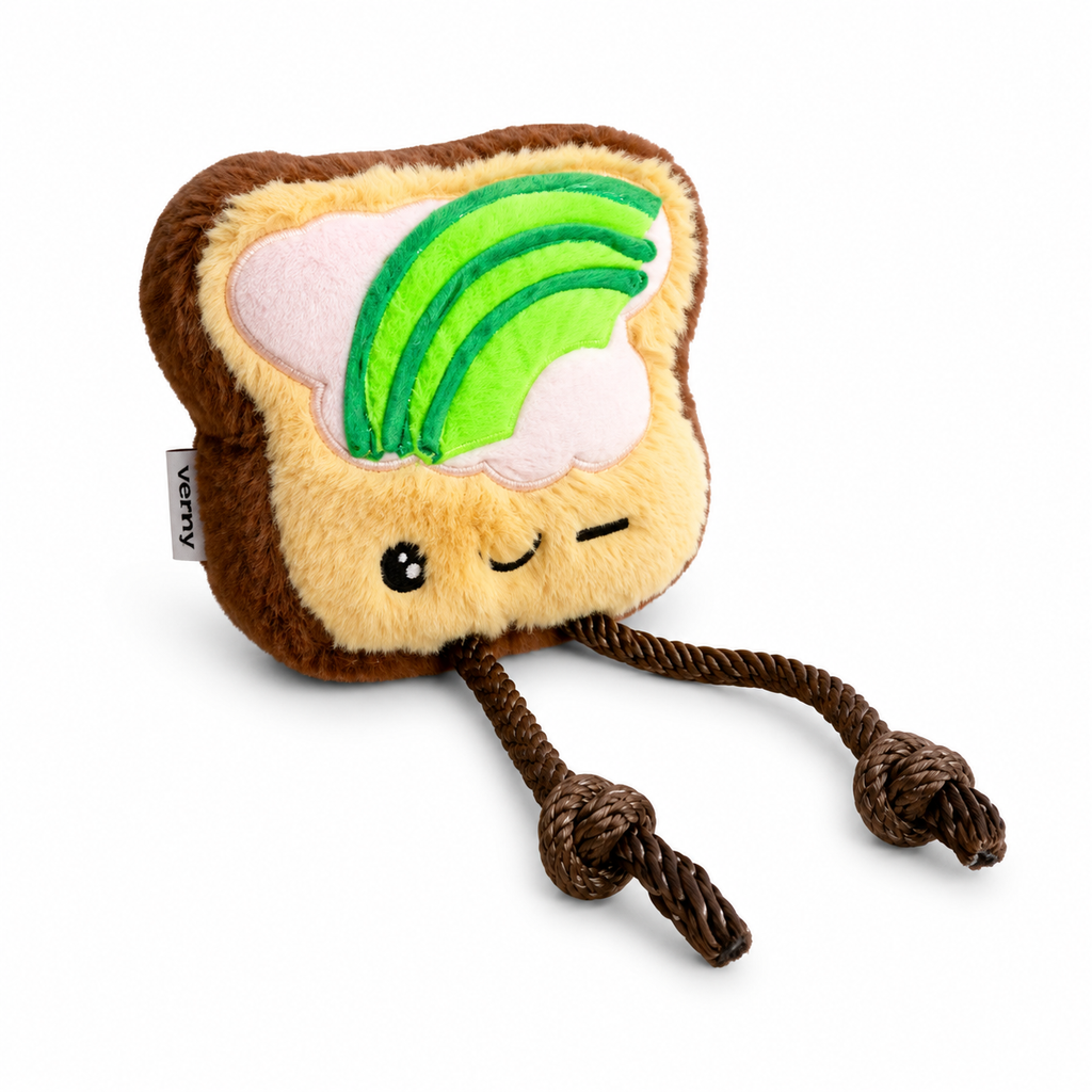 Vista en perspectiva del juguete de peluche Tosti de Verný, destacando el relieve de las rebanadas de aguacate, el grosor de la tostada y sus patas de cuerda extendidas