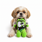 Un perro pequeño de pelaje esponjoso blanco y marrón sentado de frente, sosteniendo el juguete de peluche verde Franky de Verný entre sus patas delanteras